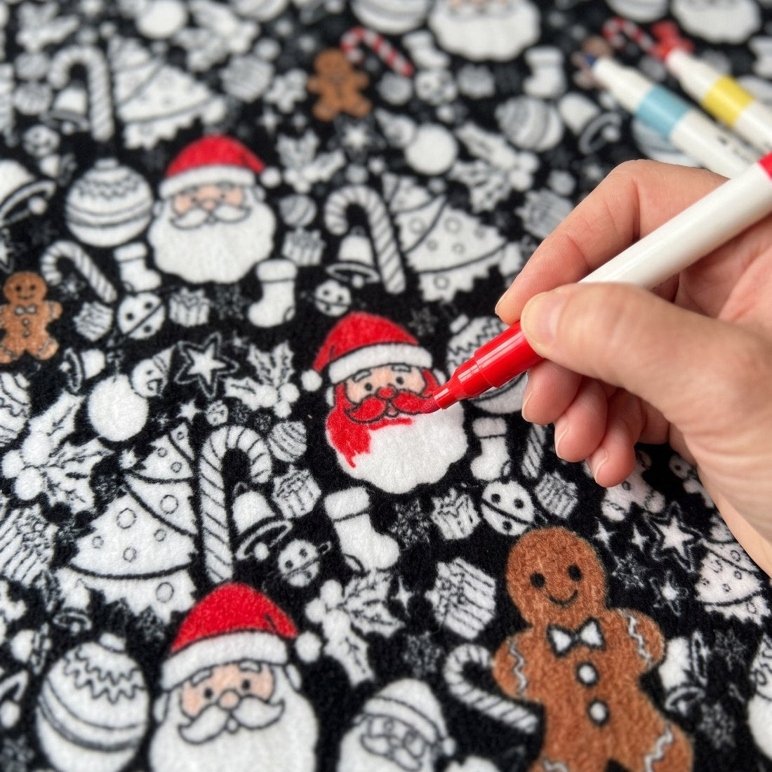 Close up of a hand coloring in a Santa with a red fabric marker