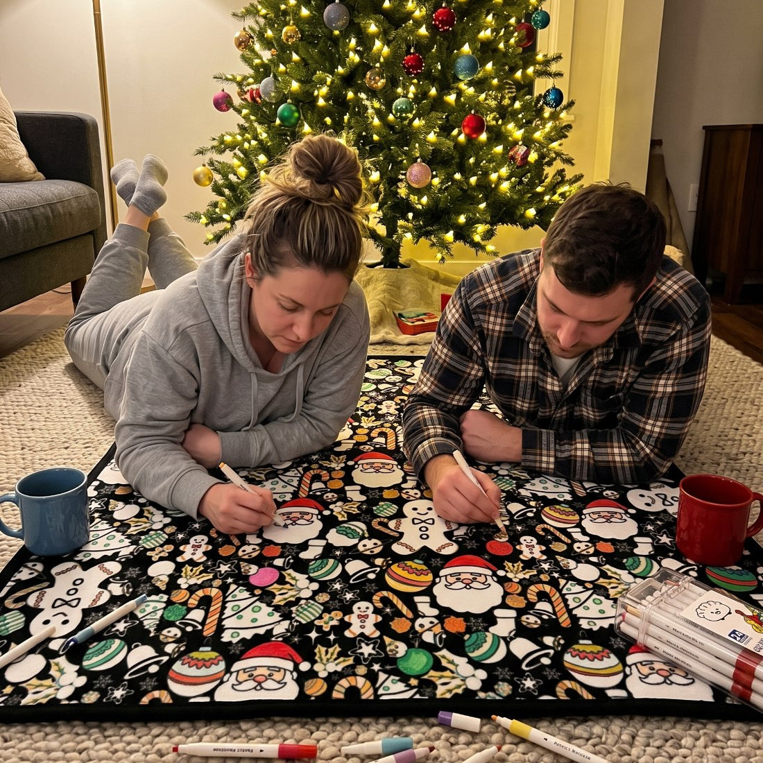 Two people lying on the floor coloring the blanket at the same time